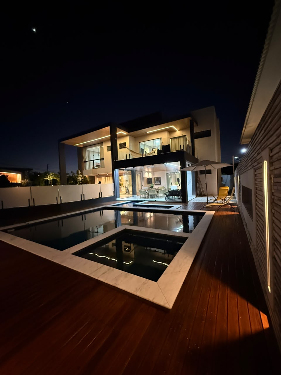 Residência iluminada vista pela piscina